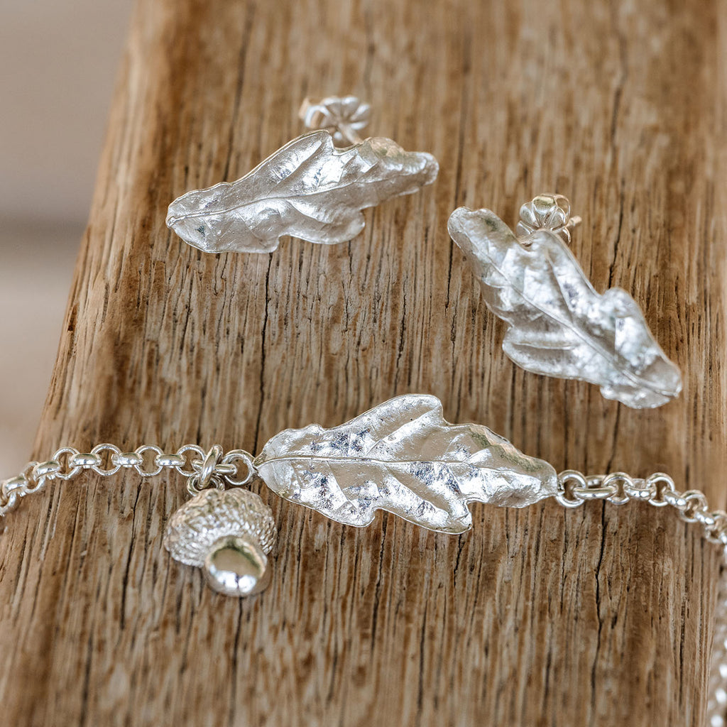 Silver Oak leaf-shaped jewelry set on a wooden surface