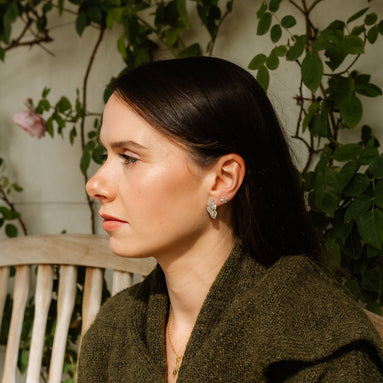 Woman sitting outdoors with greenery in the background